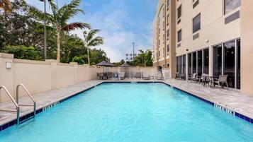 Una piscina al aire libre, sillones reclinables de piscina