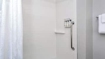 Une salle de bain moderne avec des murs recouverts de carreaux blancs, un espace douche et un porte-serviettes.