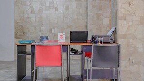 A room with a stone wall, a desk with a computer, a printer, and two chairs. - OYO 90035 Merci Club (Bandung)