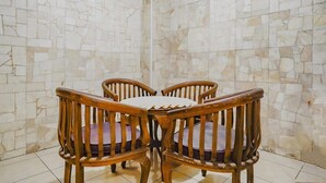 A dining area with a marble wall and wooden chairs. - OYO 90035 Merci Club (Bandung)