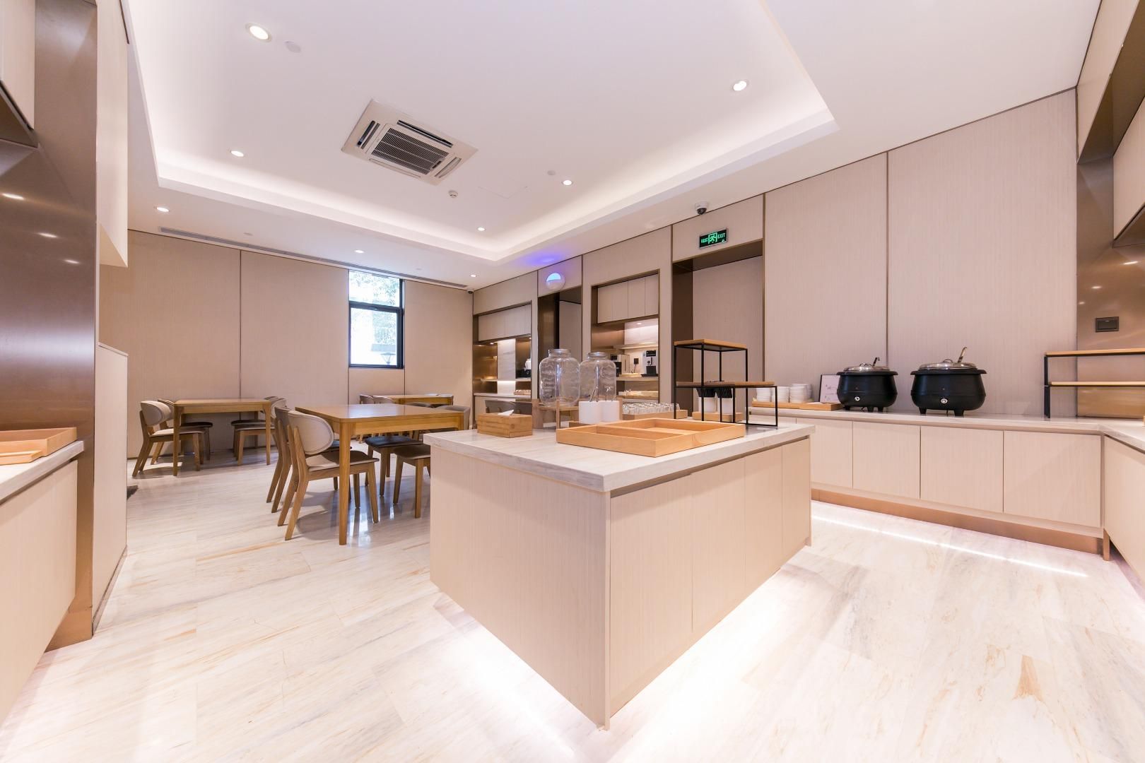 A modern kitchen with a central island, built-in appliances, and a dining area with wooden furniture.