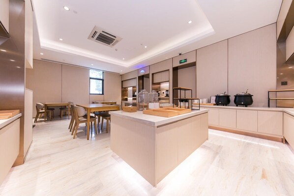 A modern kitchen with a central island, built-in appliances, and a dining area with wooden furniture.