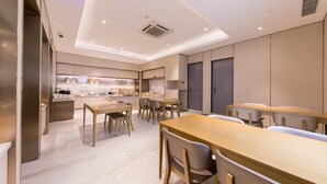 A modern hotel room with a kitchen area, dining table, and seating. - Ji Hotel (Shanghai)