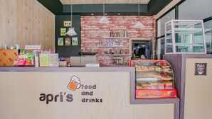 A food and drinks counter with a wooden facade, a brick wall, and hanging lights.