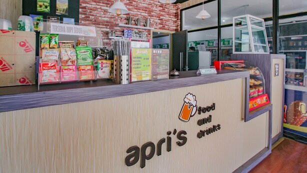 A counter with a sign reading "apri's food and drinks" and various packaged goods displayed.