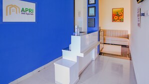A reception area with a blue wall, a white reception desk, and a beige sofa.
