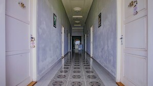 A hallway with patterned floor tiles, white doors with numbers, and a ceiling with recessed lighting.
