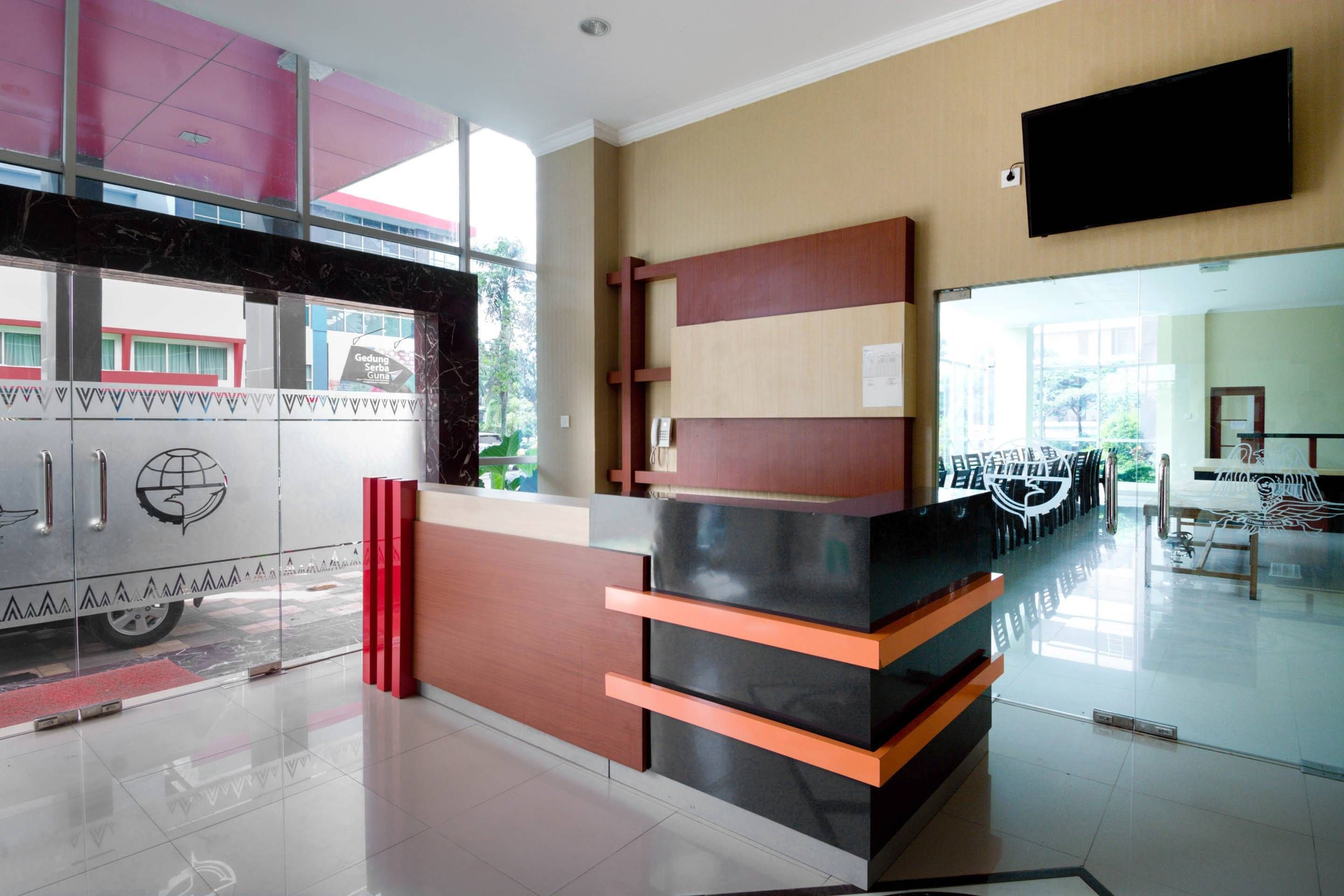 A reception desk with a modern design, a flat-screen TV mounted on the wall, and a glass door leading outside.