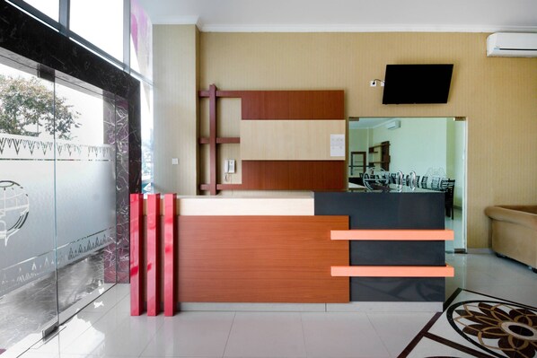 Un mostrador de recepción de diseño moderno, un televisor de pantalla plana montado en la pared y una pared de cristal que refleja el paisaje exterior.