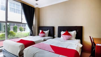 A hotel room with two beds, a large window, and a view of greenery outside.
