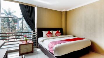 A hotel room with a bed, a desk, and a window with a view of trees.