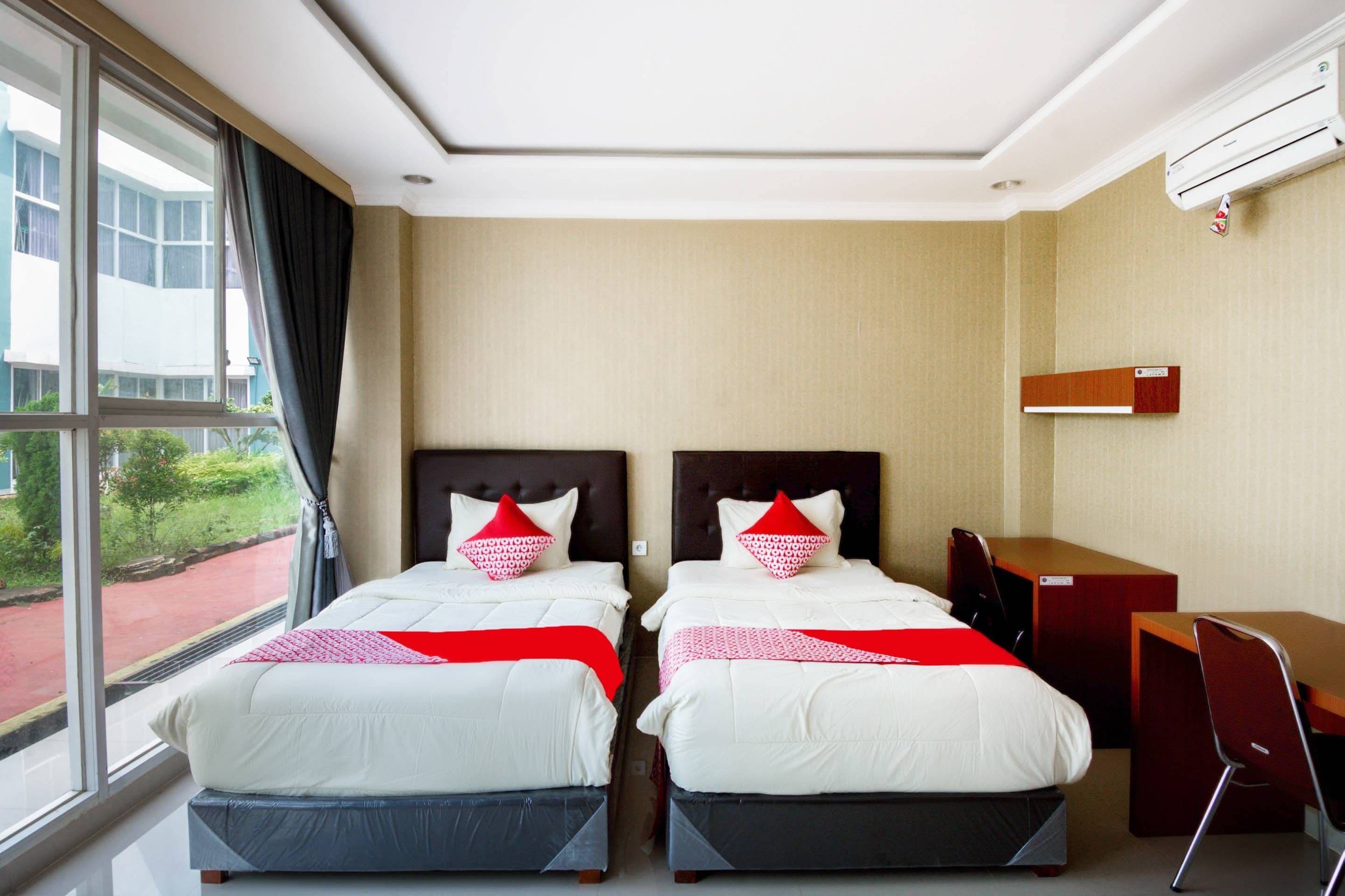 Habitación de hotel con dos camas, un escritorio y una silla.