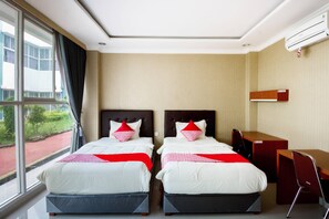 Habitación de hotel con dos camas, un escritorio y una silla.