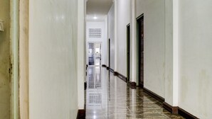 A long, narrow hallway with white walls and a polished marble floor. - Capital O 90395 Hotel Nascar Family (Palangkaraya)