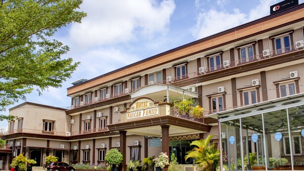 A hotel with a central entrance, multiple balconies, and a paved courtyard. - Capital O 90395 Hotel Nascar Family (Palangkaraya)