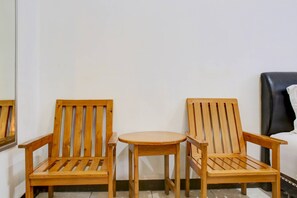 Eine Ecke eines Raumes mit zwei Holzstühlen und einem kleinen runden Tisch.