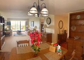 A dining area with a wooden table, chairs, a vase with flowers, and a welcome sign. - Beautiful 2 Bedroom Condo Overlooking IMG Academy Golf Course (Bradenton)