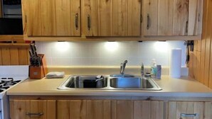A kitchen with wooden cabinets, a stainless steel sink, and a stove. - Ursa Miner - quiet, dark sky, 6 miles from Pitkin! (Parlin)