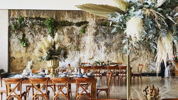 A dining area with wooden tables and chairs, a rustic stone wall, and decorative plants. - BV Hotel Atlixco (Atlixco)