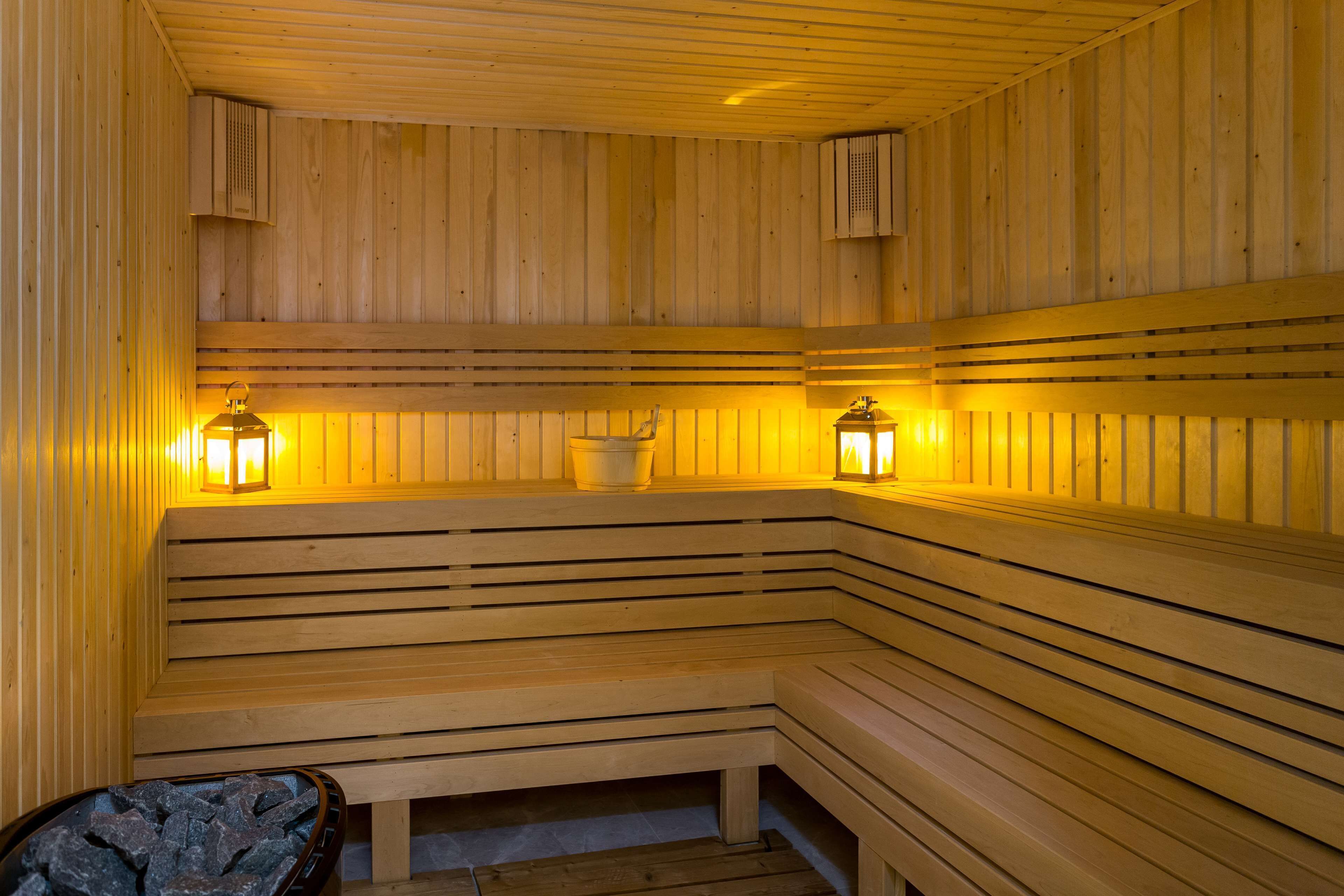 A sauna with wooden benches and two wall-mounted heaters.