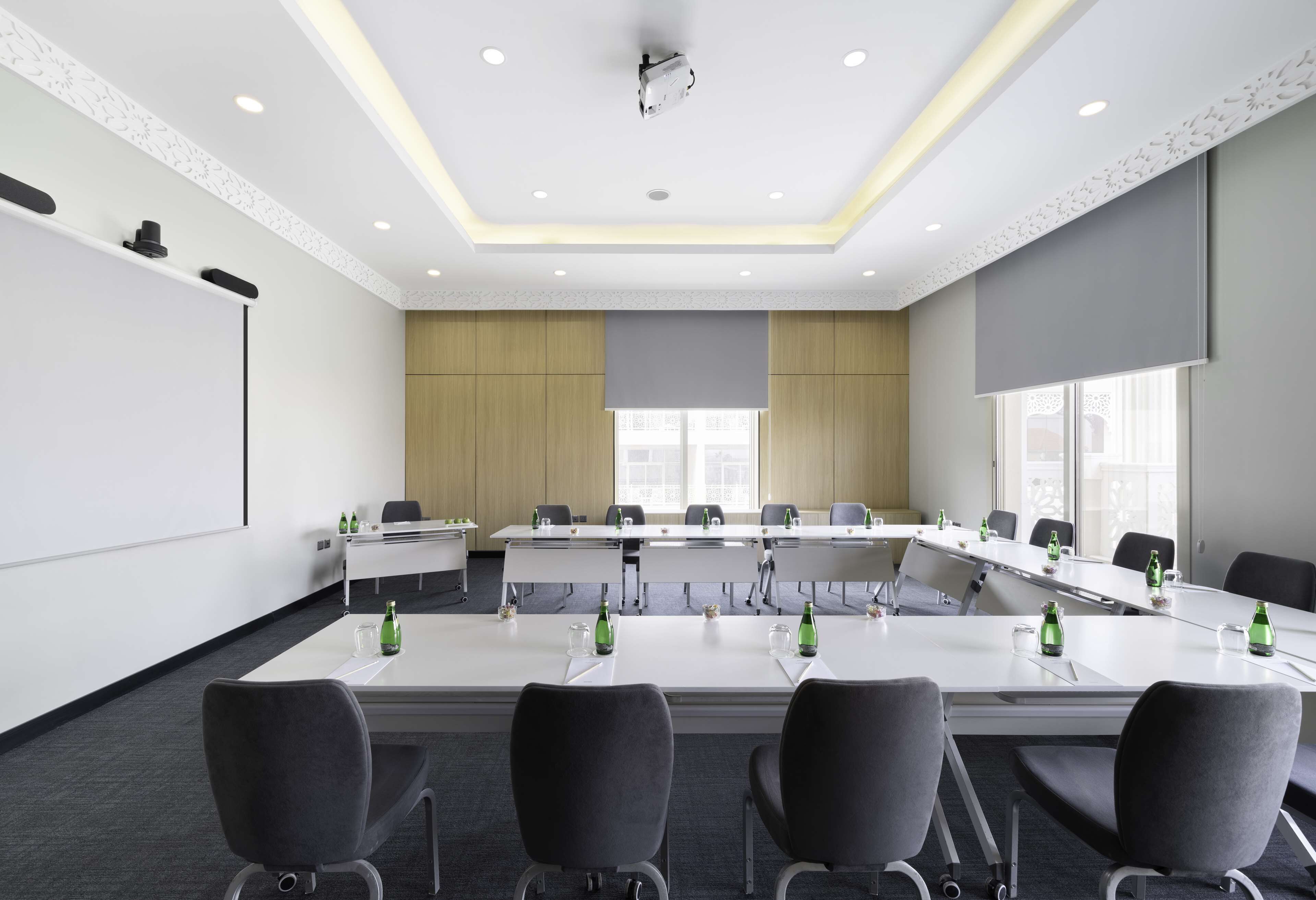 Une salle de conférence équipée d’une longue table, de nombreuses chaises et d’un écran de projection.