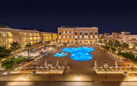 A hotel with a large central pool, multiple balconies, and a well-lit outdoor area.
