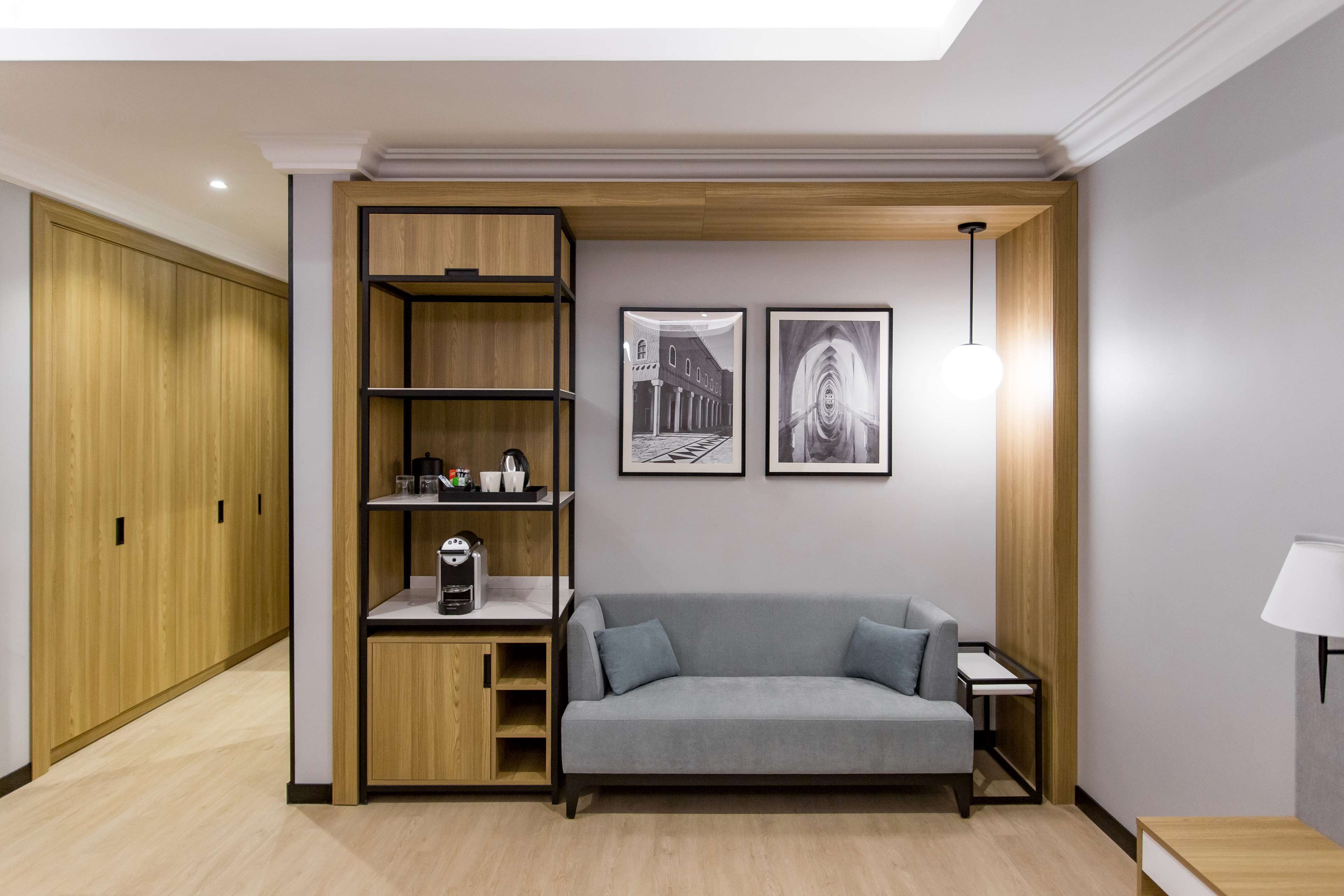 A modern room with a grey sofa, wooden shelving unit, and two framed pictures on the wall.