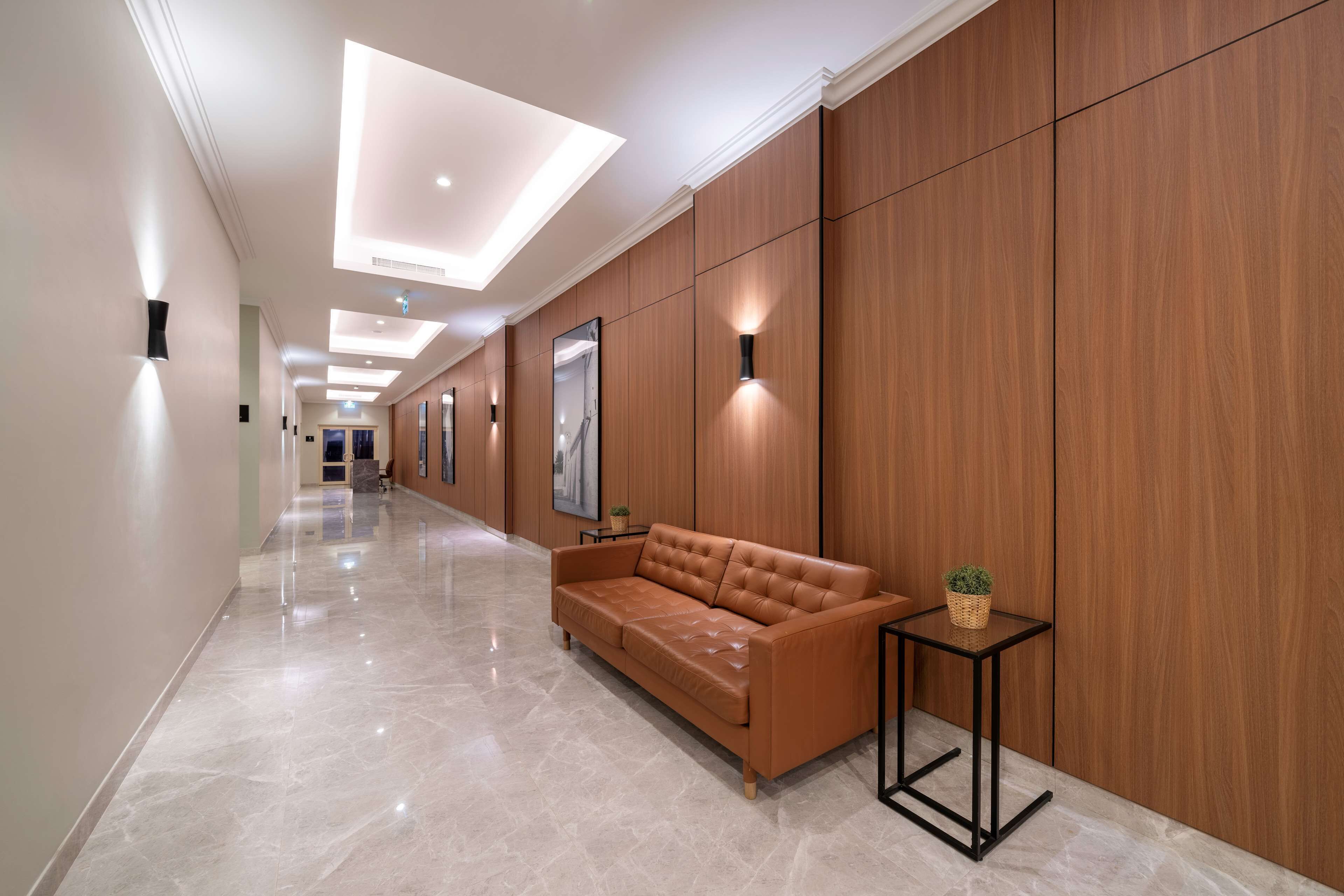 A hallway with a leather sofa, a small table with a plant, and wooden paneling on the walls.