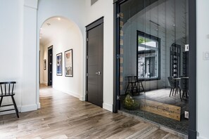 Ein modernes Interieur mit Holzboden, einem Glastür-Eingang und einem durch die Glastür erkennbaren Essbereich.