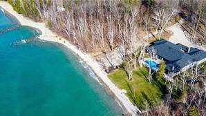 Vue aérienne d’une propriété située sur la côte, avec une maison, une piscine et une plage.