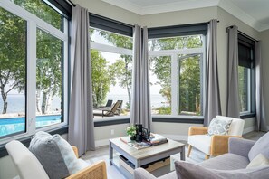 Une pièce dotée de grandes fenêtres, d’une piscine et d’un espace extérieur aménagé près de la piscine.