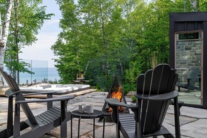An outdoor seating area with Adirondack chairs, a hot tub, and a fire pit.