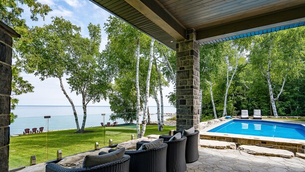 Un espace piscine aménagé avec des meubles en osier et offrant une vue sur la mer.