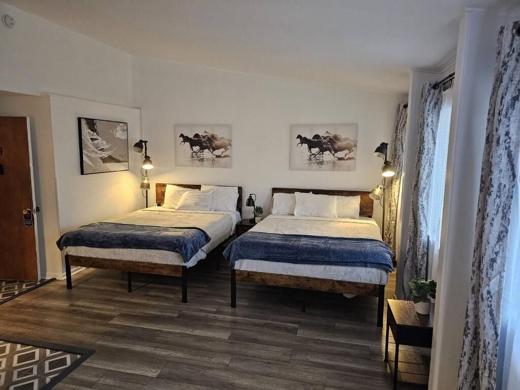 Ein Zimmer mit zwei Betten, Holzboden und einer Tür.