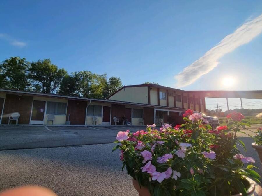 A motel with multiple rooms, a parking lot, and a clear sky.