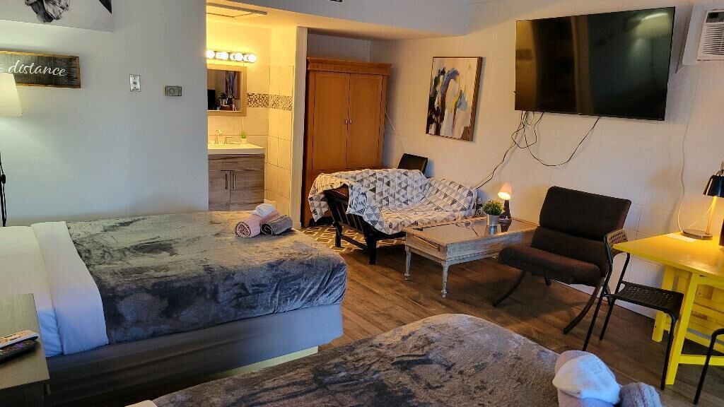 Une chambre à coucher de taille réduite, comprenant un lit, une petite table, une chaise, un téléviseur et une armoire.