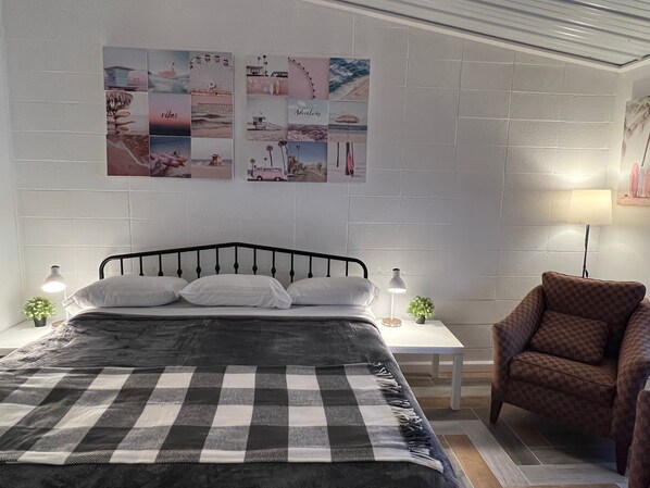 A bedroom with a bed, a chair, a nightstand, and wall art. - Sussex Motel (Sussex)