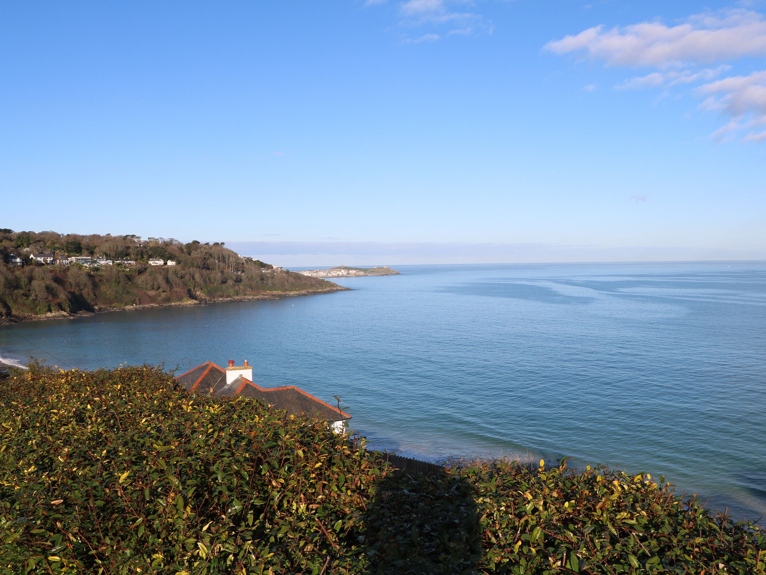 A coastal view with a house on a hill overlooking the sea.