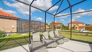 A covered outdoor area with a pool, lounge chairs, and a view of residential buildings. - Stunning mediterranean styled home in the exclusive Providence Golf community 2562 (Davenport)