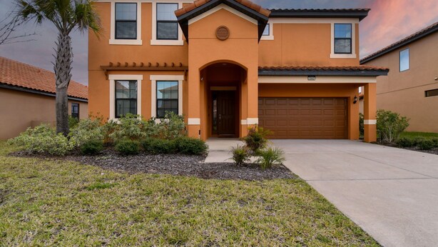 A two-story house with a brown facade, a front entrance with an arch, and a garage door. - Stunning mediterranean styled home in the exclusive Providence Golf community 2562 (Davenport)