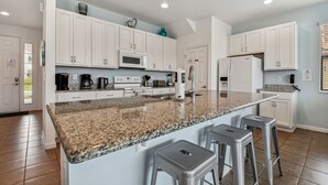 A modern kitchen with white cabinets, granite countertops, and stainless steel appliances. - Stunning mediterranean styled home in the exclusive Providence Golf community 2562 (Davenport)