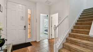 A hallway with a white door, a glass door, and a staircase with a white railing. - Stunning mediterranean styled home in the exclusive Providence Golf community 2562 (Davenport)