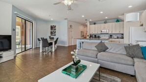 A modern living room with a grey sofa, a coffee table with a decorative tray, and a ceiling fan. - Stunning mediterranean styled home in the exclusive Providence Golf community 2562 (Davenport)