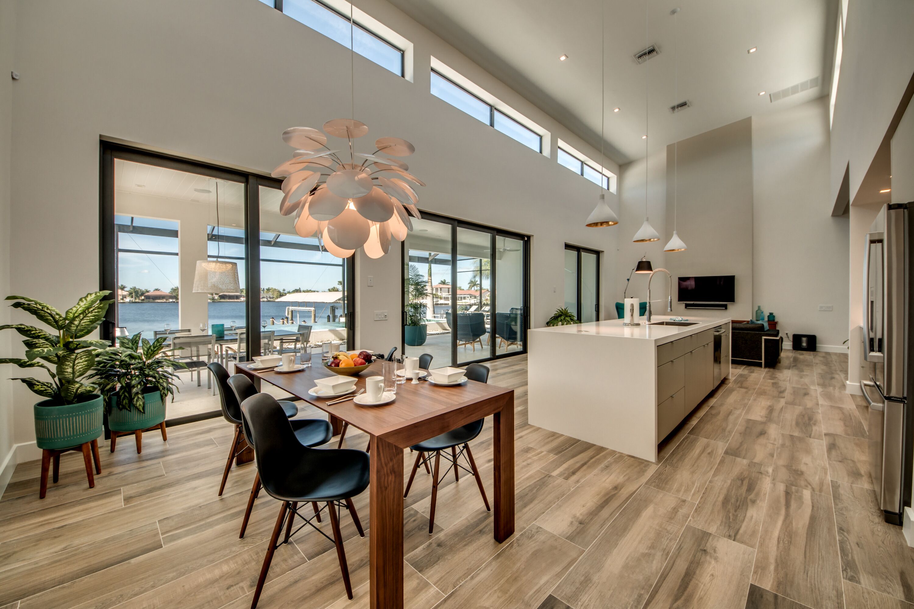 A modern kitchen with a large island, dining area with chairs, and large windows overlooking a scenic view.