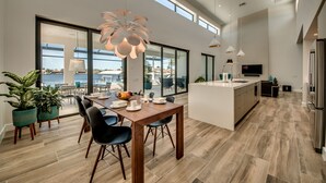 Una cocina moderna con una isla grande, comedor con sillas y ventanas amplias con vistas panorámicas.
