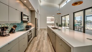 Una cocina moderna con una encimera amplia, electrodomésticos de acero inoxidable y vistas al exterior.