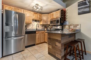 Eine moderne Küche mit Holzausstattung, Edelstahlgeräten und einer Granitabdeckung.