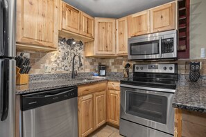 A kitchen with wooden cabinets, stainless steel appliances including a refrigerator, dishwasher, microwave, and oven.