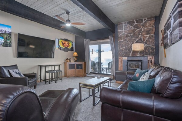 A cozy living room with a fireplace, leather furniture, and a stone accent wall.