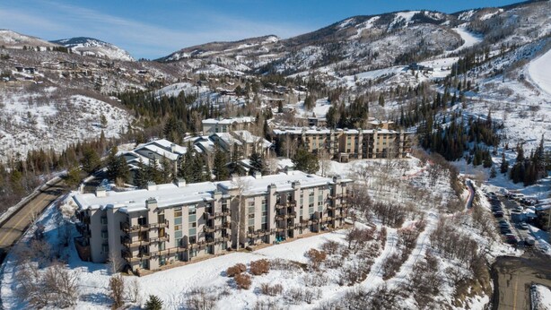 Un gran hotel con varias edificaciones, rodeado de montañas nevadas y una pista de esquí.